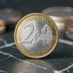 Pièce de 2 euros commémorative JO 2026 avec la Tour Eiffel en gros plan sur ardoise sombre